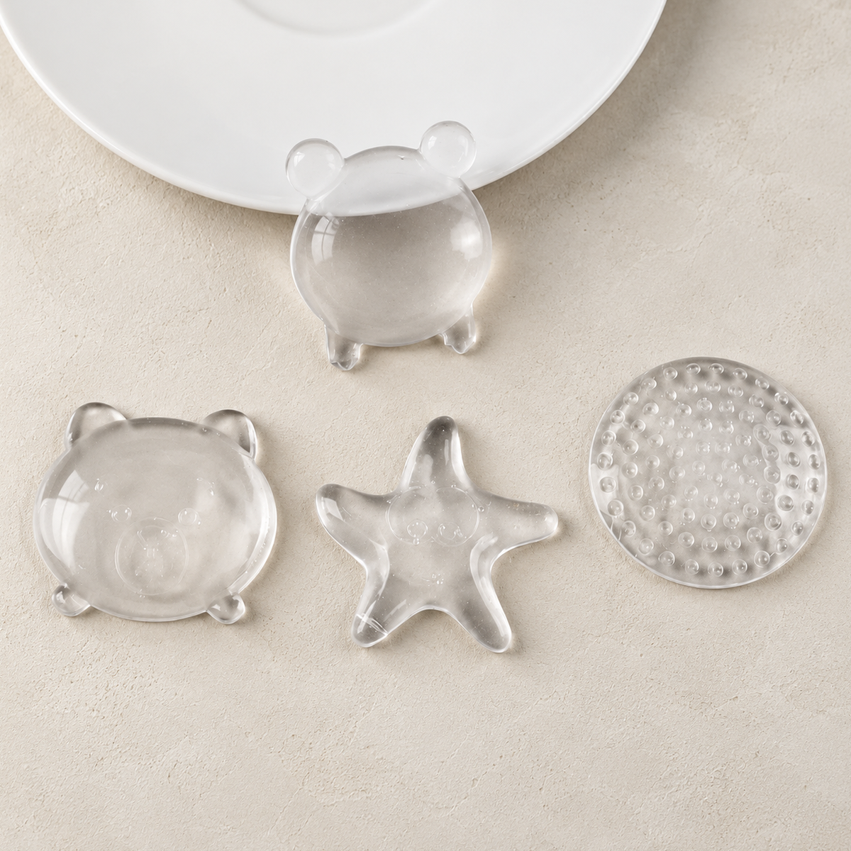 Clear silicone wall protectors in bear, frog, sea star and round shapes on a cream surface